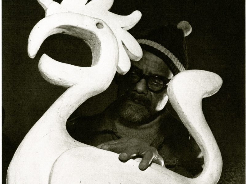 Abstract white sculptural form with branching, tentacle-like appendages against a dark background